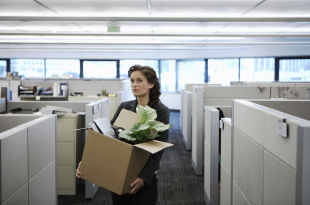 Young businesswoman carrying cardboard box in office, portrait