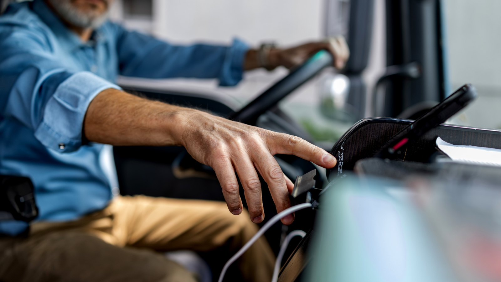 Experienced Professional Driver Operating Vehicle Dashboard and Mobile Device for Logistics Workflow