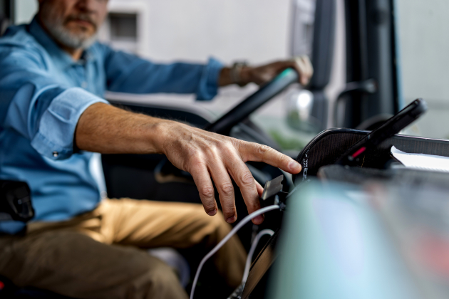 Experienced Professional Driver Operating Vehicle Dashboard and Mobile Device for Logistics Workflow