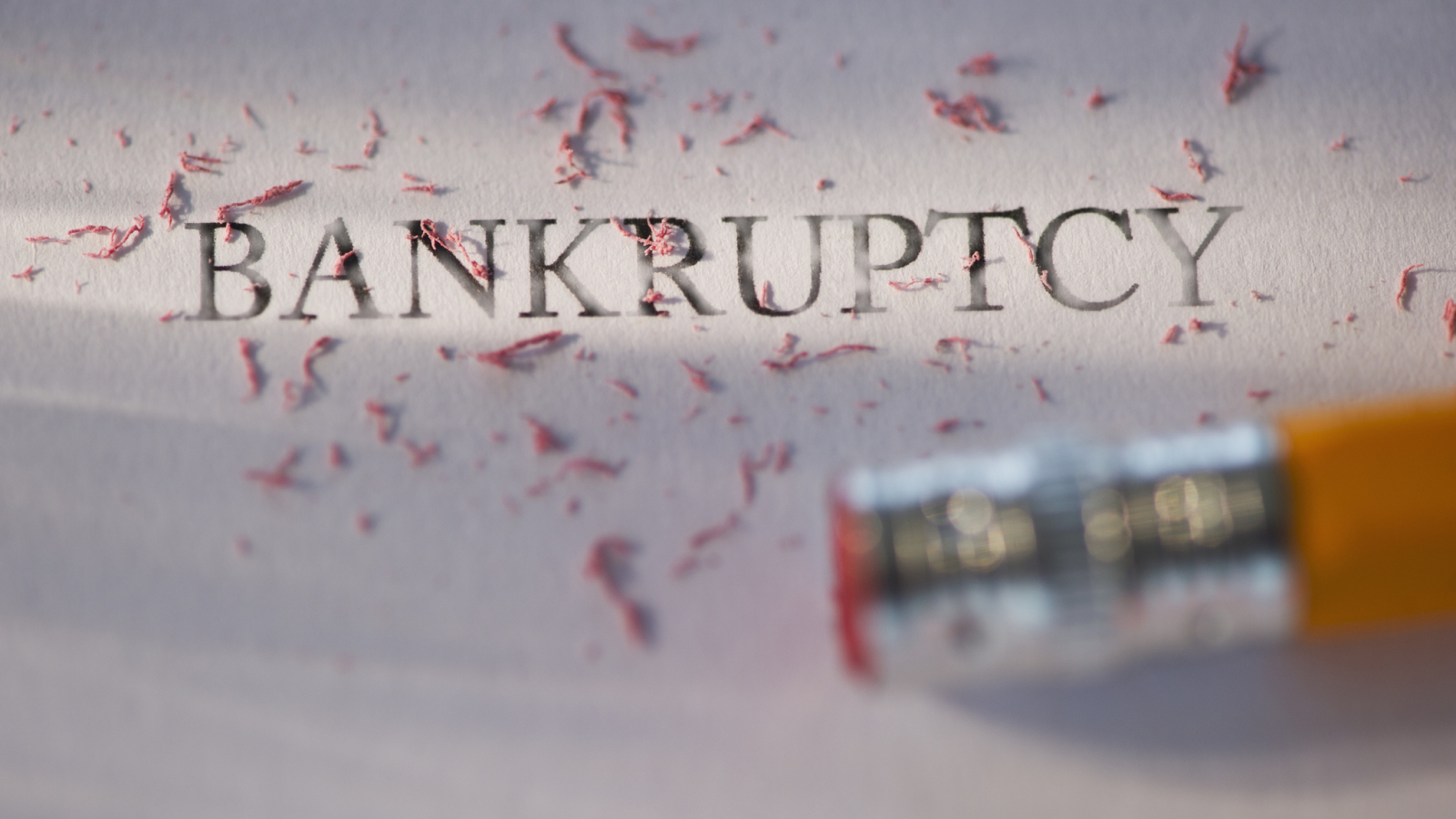 Studio shot of pencil erasing the word bankruptcy from piece of paper