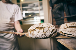 Baker putting bread into oven in his bakery