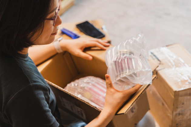 over the shoulder view of asian woman unpack the package she ordered online