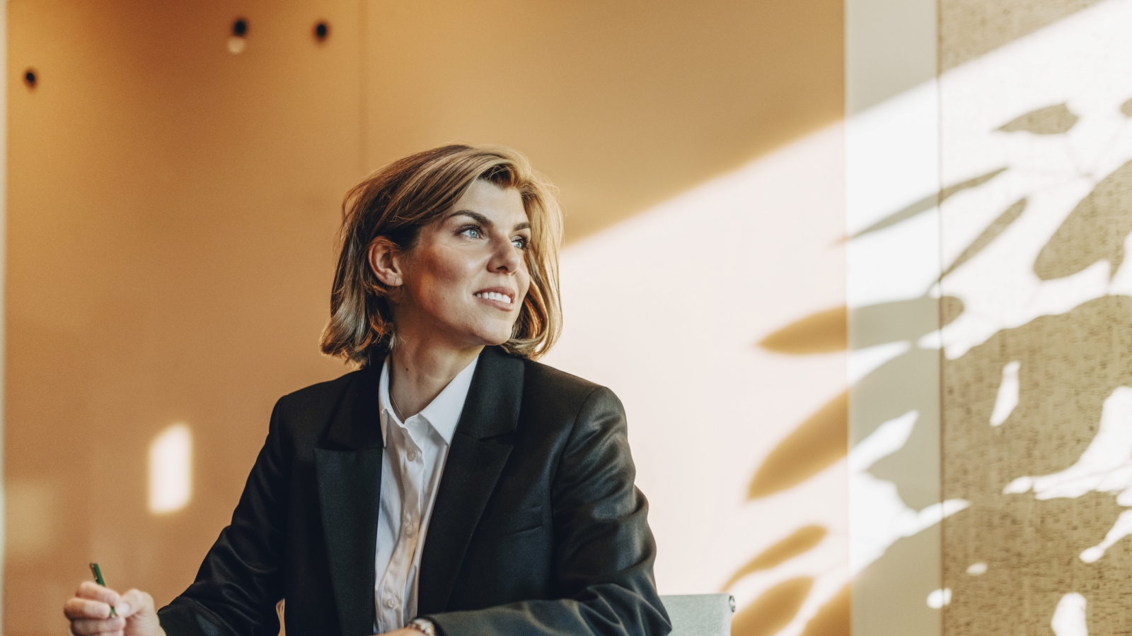 Low angle view of smiling female lawyer looking away while sitting at table in office board room