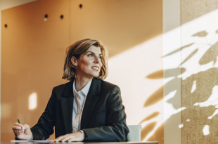 Low angle view of smiling female lawyer looking away while sitting at table in office board room