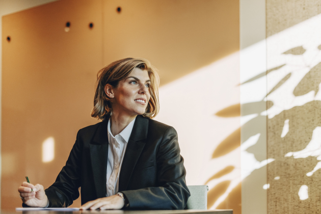 Low angle view of smiling female lawyer looking away while sitting at table in office board room