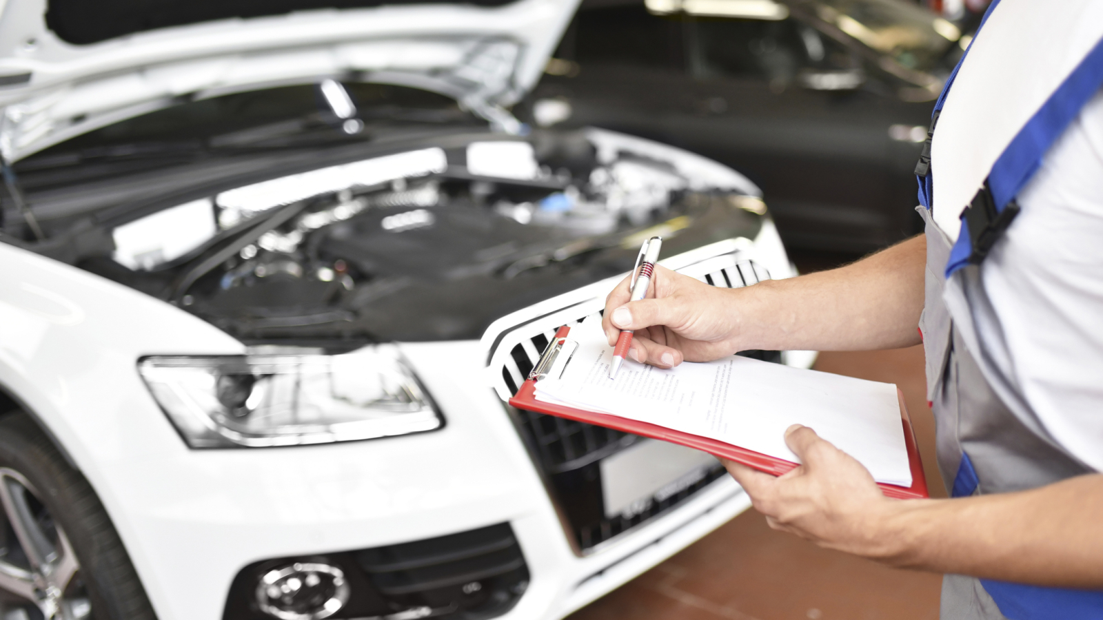 Car mechanic holding clipboard in a garage
