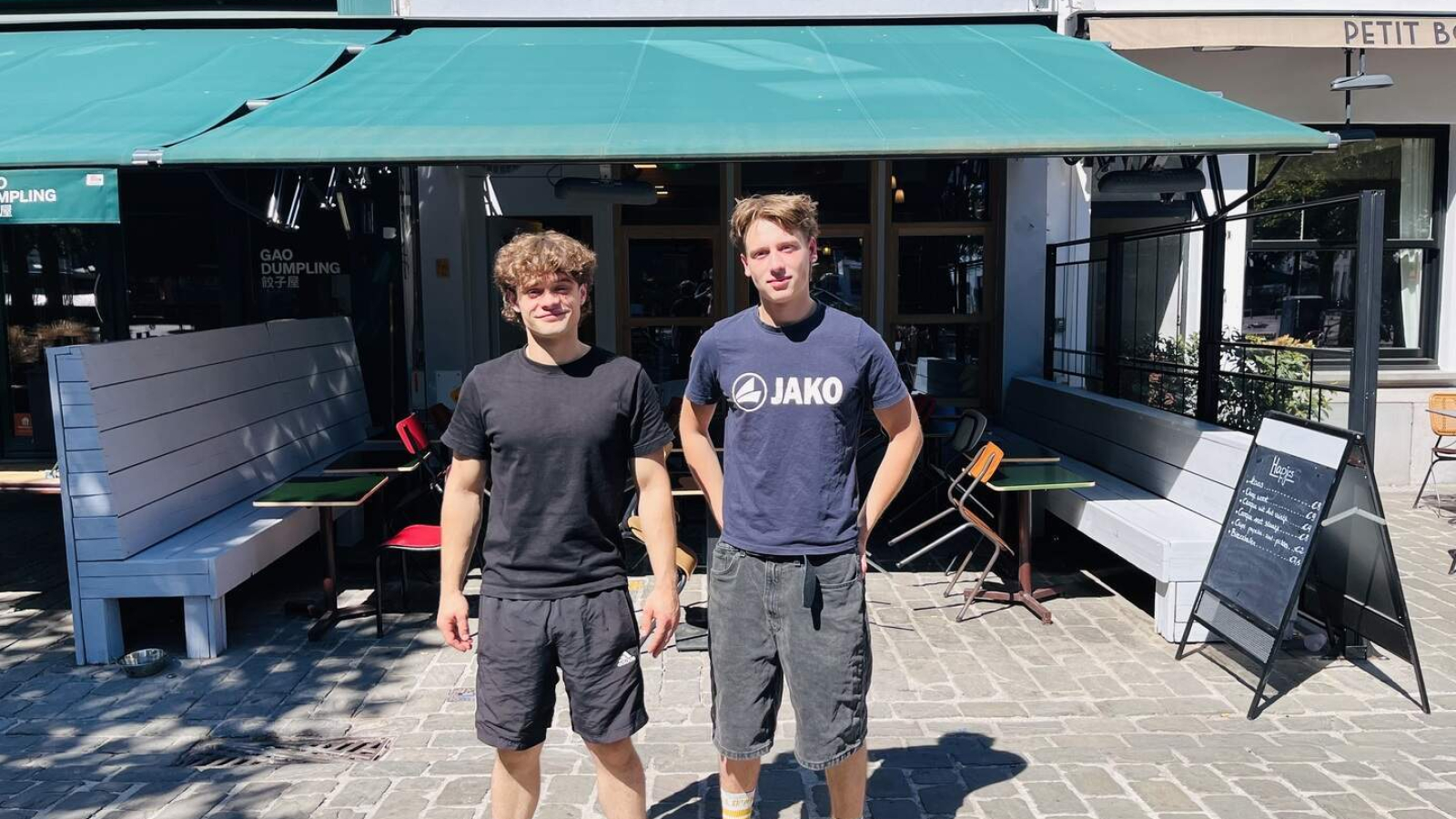 Felix en Adam poseren voor de gevel van café Belgica