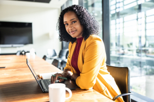 Portrait of businesswoman using laptop in modern conference room