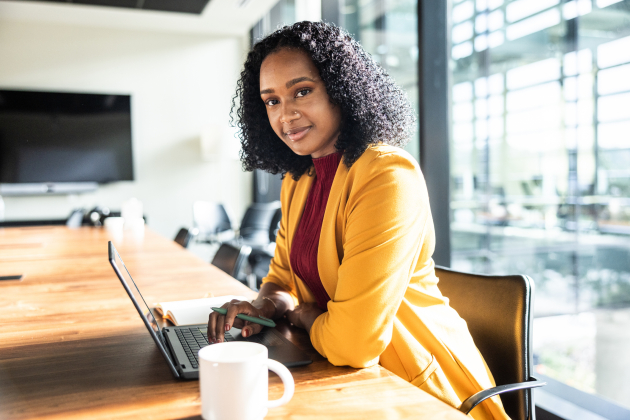 Portrait of businesswoman using laptop in modern conference room